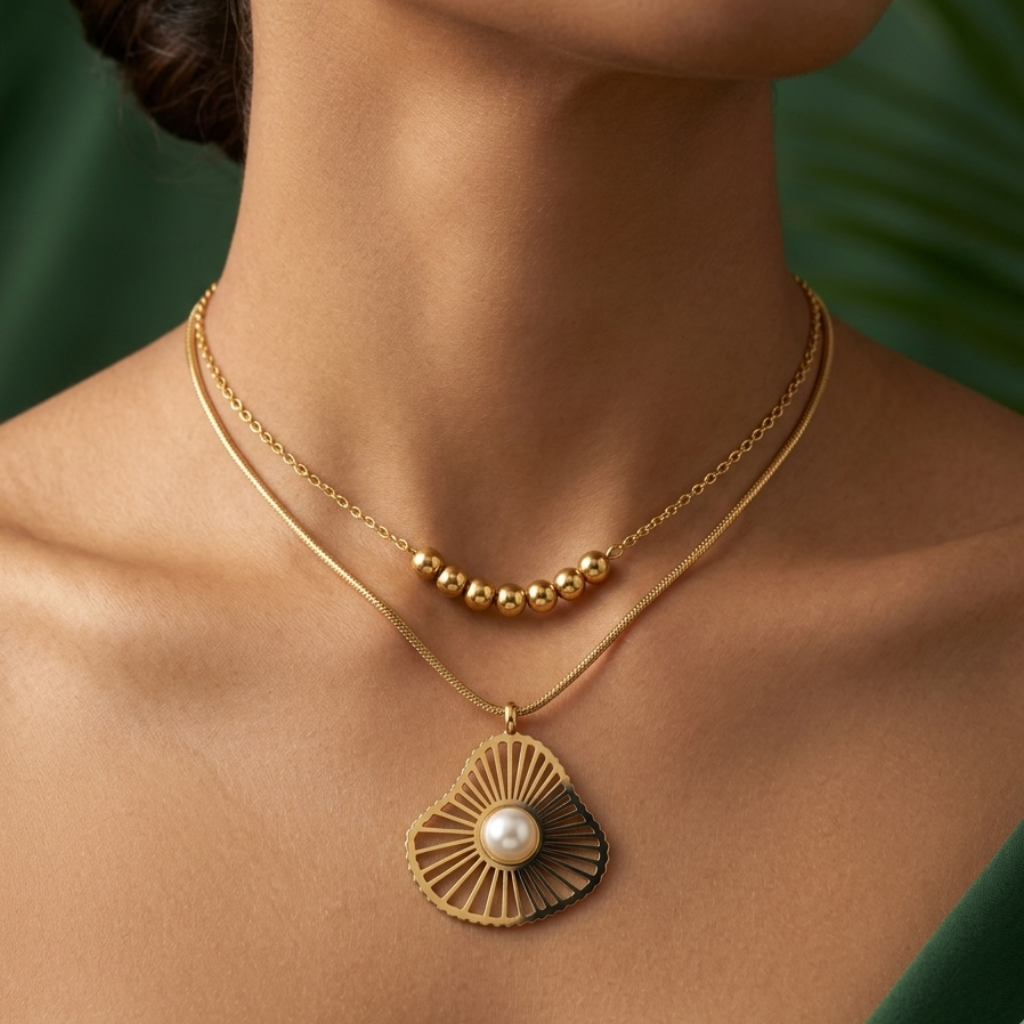 Gold necklace with a pearl pendant on a person against a green background