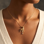 A close-up of a model wearing a delicate gold chain necklace with a small deer pendant and a tiny dangling star charm, styled with a cream-colored knit V-neck top.