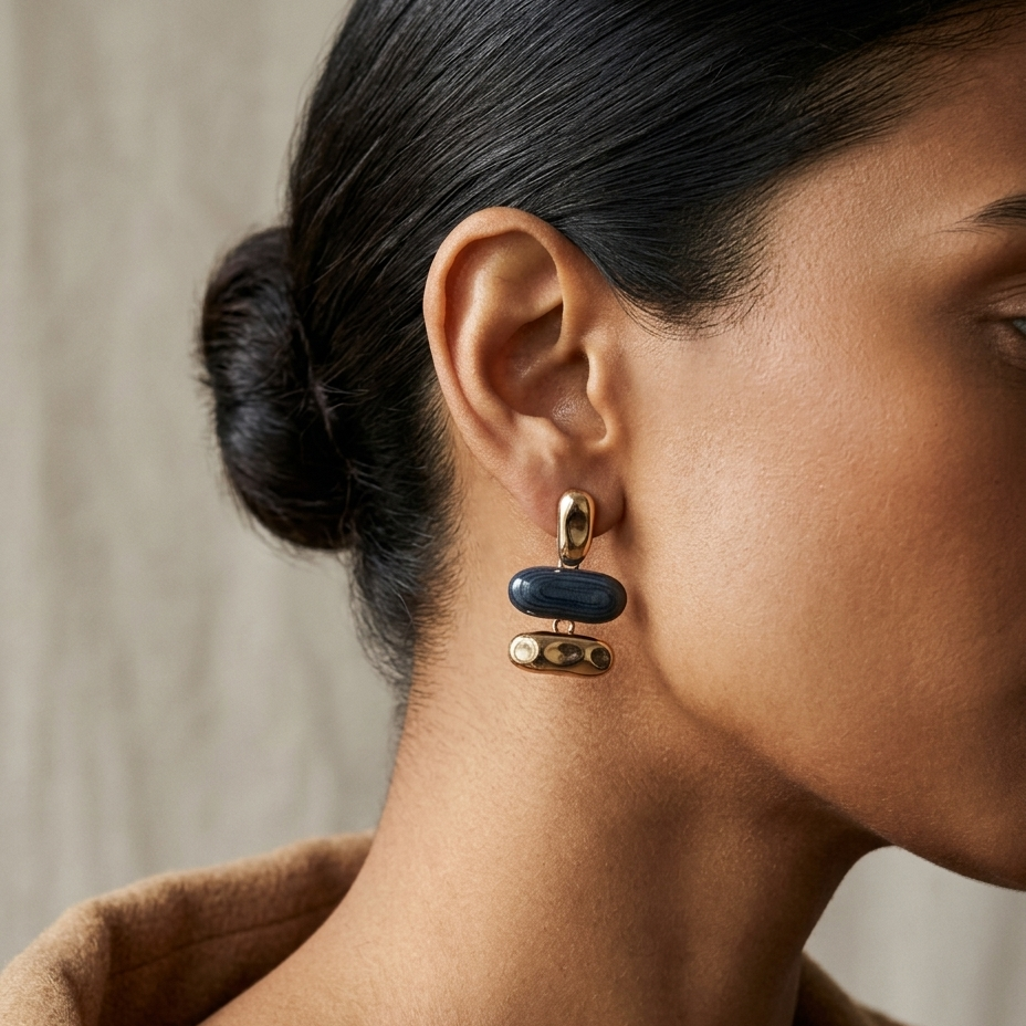 A close-up side profile of a woman wearing a gold and dark blue geometric drop earring.