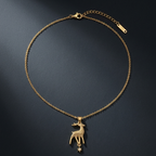 A delicate gold chain necklace featuring a small deer pendant with a dangling star charm, displayed on a dark textured background.