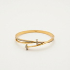 A gold hinged bangle bracelet with a twisted cross design, accented with small pavé-set clear stones, photographed on a clean white background.