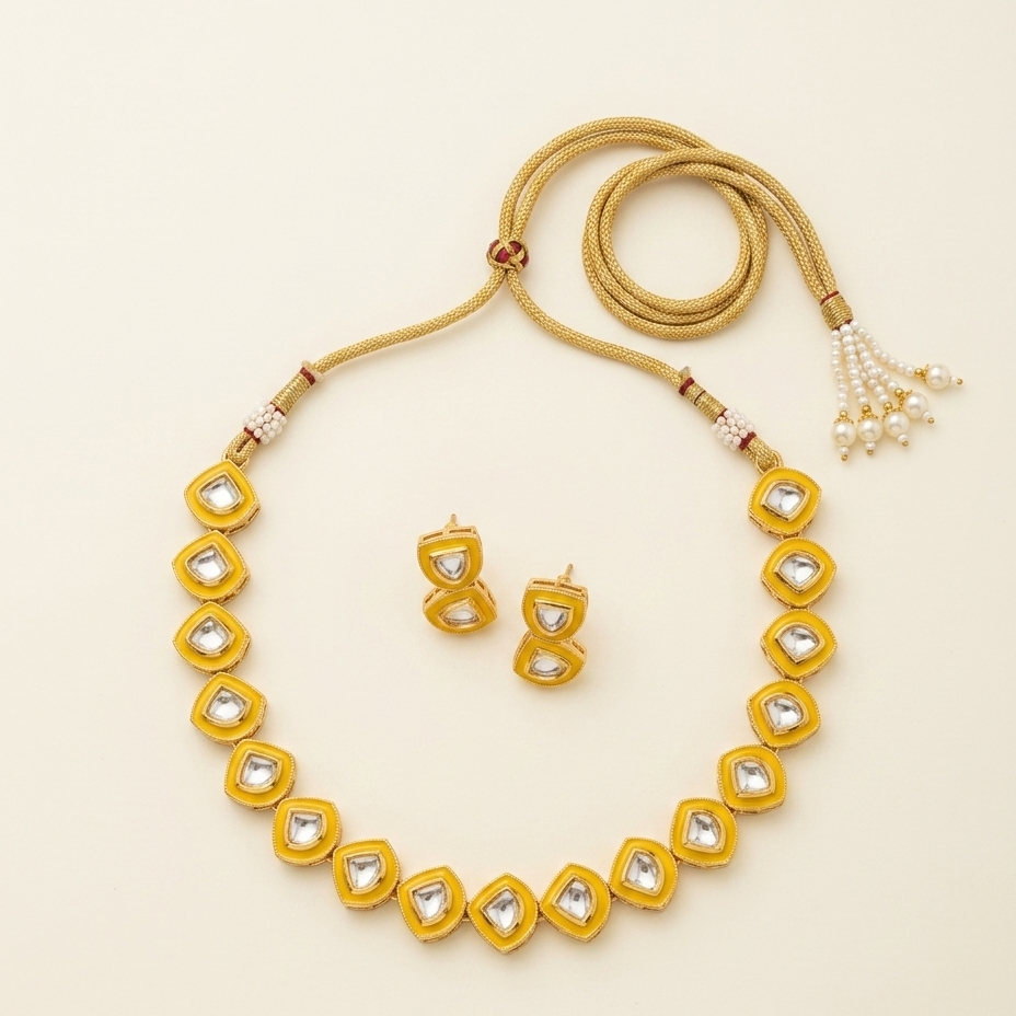 A gold jewelry set featuring a necklace, matching earrings, and a beaded cord accessory, arranged on a light cream background.