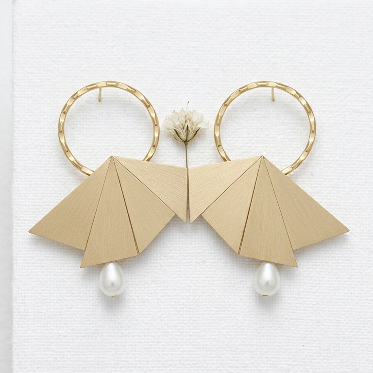A pair of gold hoop earrings with geometric fan-shaped drop elements and small pearl drops, displayed on a white textured card.