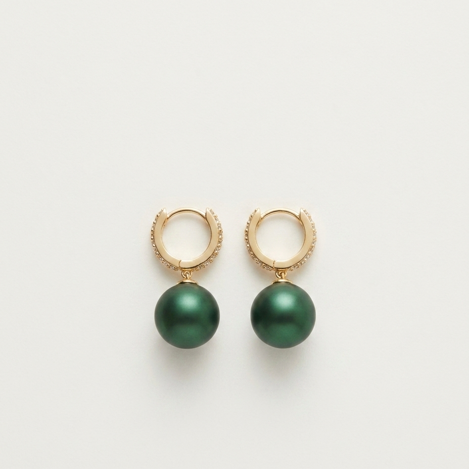 A pair of gold huggie hoop earrings with dangling dark green pearl-like drops, shown on a clean off-white background.