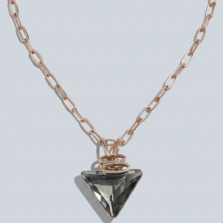 A rose gold chain necklace with a faceted triangular pendant, displayed on a light gray background.