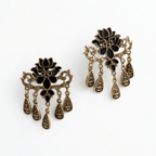 Black and antique gold lotus drop earrings with dangling design by Yugavi on clean background