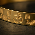 Gold bracelet with Om symbol on a dark background