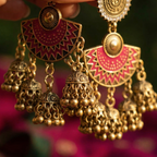 Close-up of Yugavi Devanshi magenta enamel arch connector — deep pink chandbali half-moon form with antique gold geometric zigzag and triangle border engraving, central polished gold dome, three jhumka links visible below