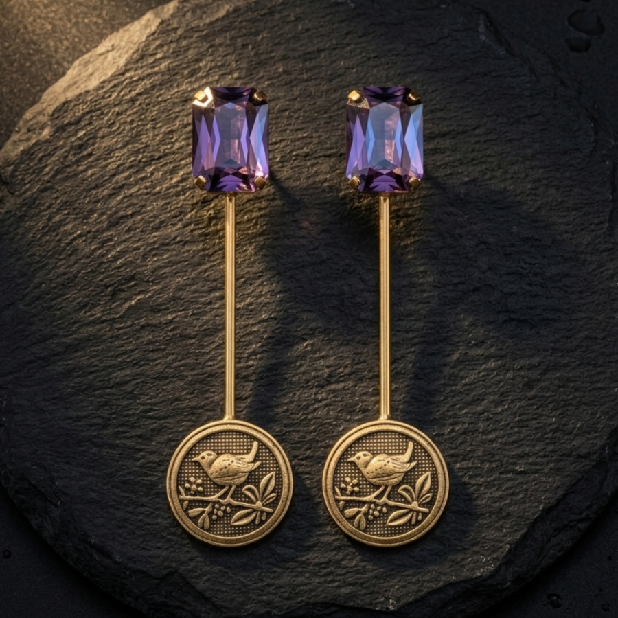 Gold earrings with purple gemstones on a dark stone surface