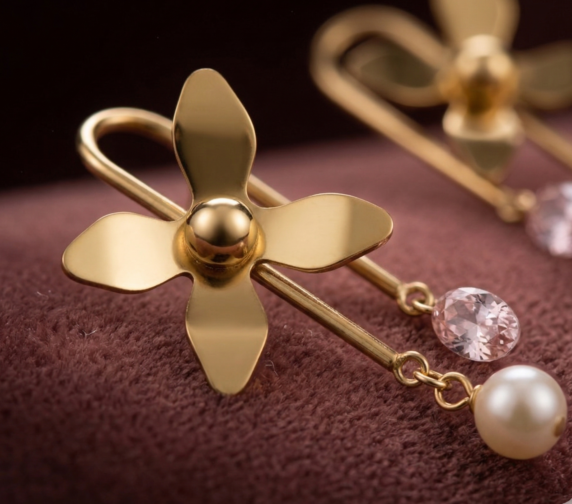 Close-up of Yugavi Kanika Earrings — high-polish gold four-petal flower, blush pink oval CZ and cream pearl-look drop detail