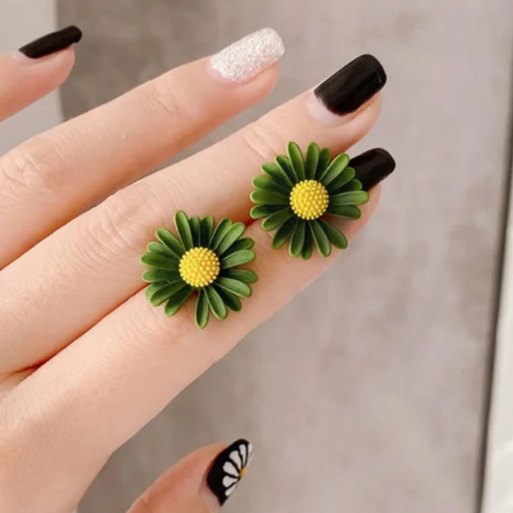 Close-up of Yugavi Kavya earring centre — raised textured dome of individual yellow pollen spheres surrounded by ribbed forest green daisy petals, matte enamel-effect finish on dark green flower stud earring