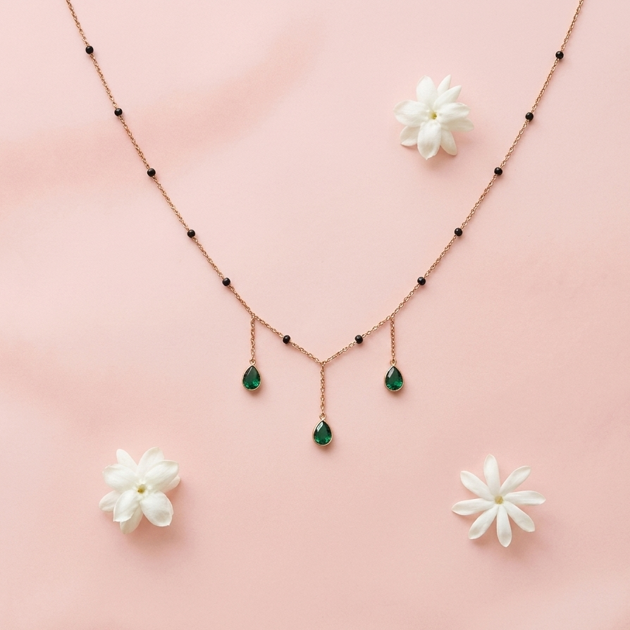 Necklace with emerald drops and matching earrings on a pink background
