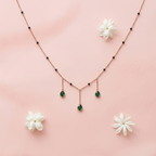 Necklace with emerald drops and matching earrings on a pink background