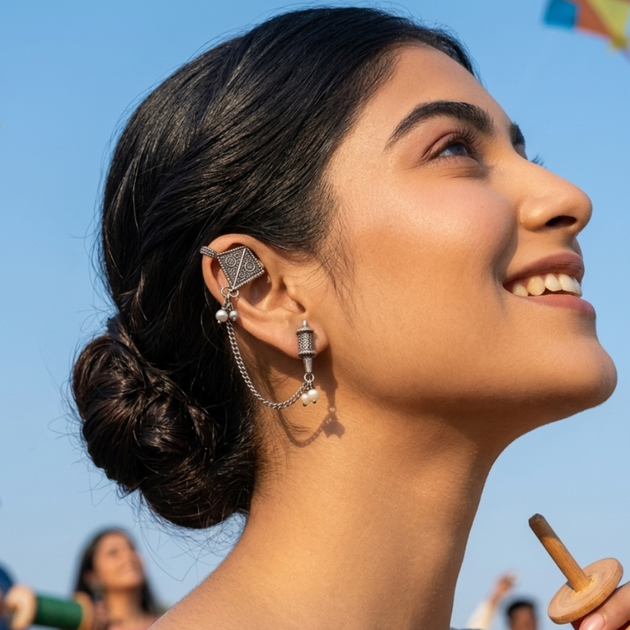 Woman with stylish earrings looking up at kites against a blue sky