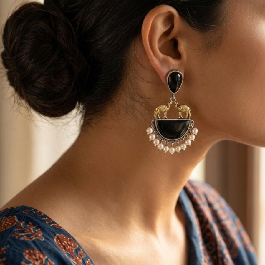 Close-up of a woman wearing an ornate earring with black and pearl details.
