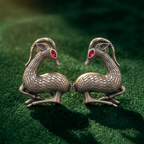 Pair of dragon-shaped earrings on a green textured surface