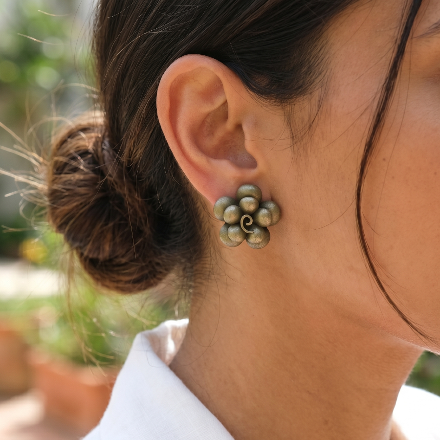 Close-up of a person wearing floral earrings with a blurred outdoor background