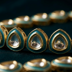Close-up of a gold and turquoise bracelet with clear teardrop-shaped stones, set against a dark navy background.