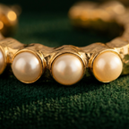 Detail of Yugavi Ishira gold hoop band texture — hammered faceted gold surface catching directional light on the C-hoop earring, showing the irregular worked texture of the band between the pearl fringe stations