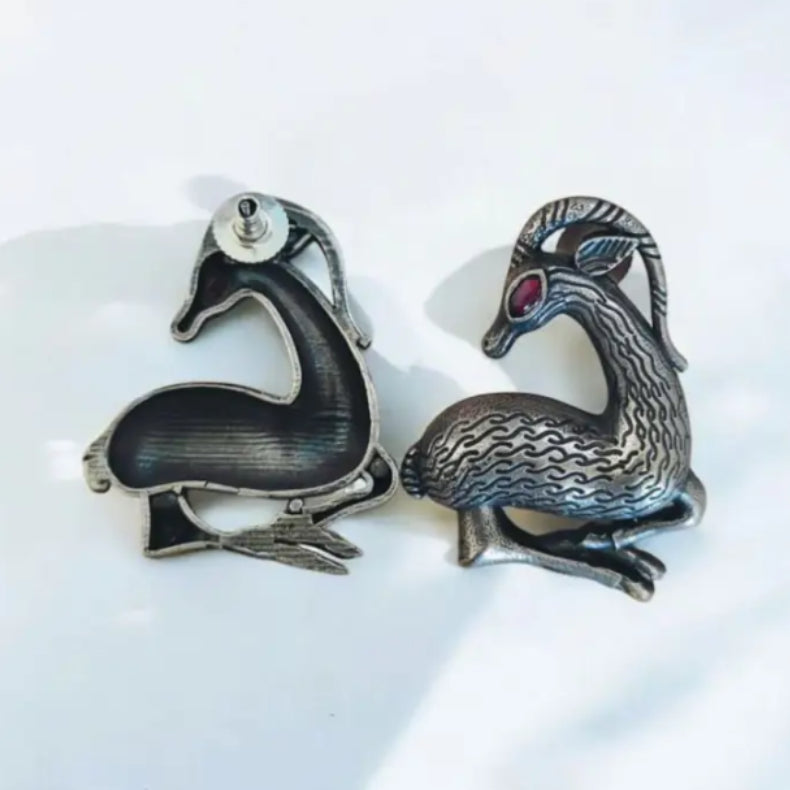 Detail of Yugavi Rithvika ruby red crystal eye — single marquise leaf-shaped ruby faceted crystal in gold-toned bezel at the eye of the oxidised silver Hamsa bird sculpture stud earring, vivid crimson against the grey-silver engraved body, sacred bird jewellery India House of Yugavi
