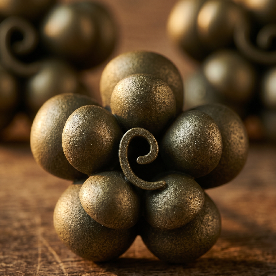 Close-up of a bronze decorative object resembling a cluster of grapes on a wooden surface