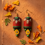 Dhaṭṭī hand-painted terracotta cylinder drop earrings in red, green, black and yellow folk art design by House of Yugavi Boho collection, white background