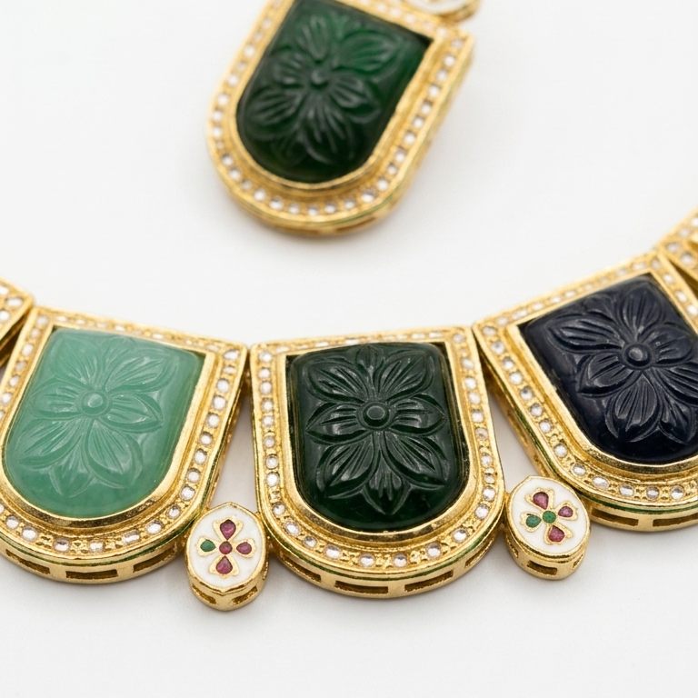 Gold-tone necklace with rectangular carved stone panels in green, teal, and black, accented with small red and green stones, on a white background.