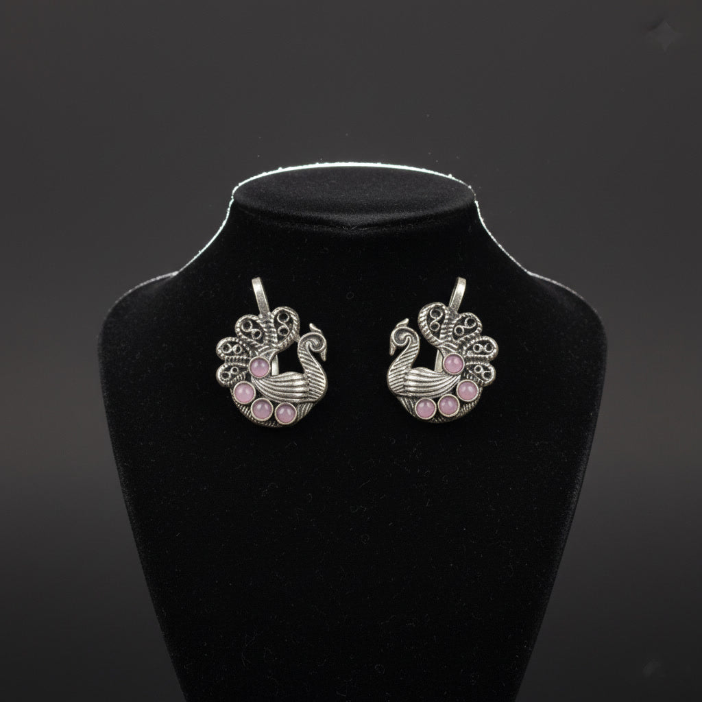 Silver earrings with pink stones on a black stand against a dark background