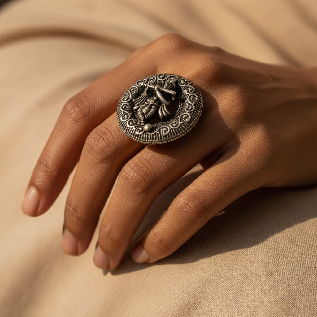 Hand wearing a decorative silver ring on a beige fabric background