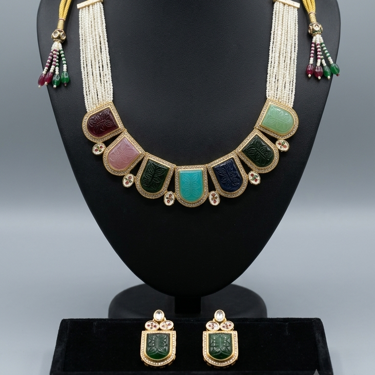 A gold-tone statement necklace and matching drop earrings displayed on a black mannequin bust. The necklace features a wide collar design with gold-toned fringe, gold-toned shield-shaped bezels, and multiple colored stones including turquoise, green, pink, and dark blue.