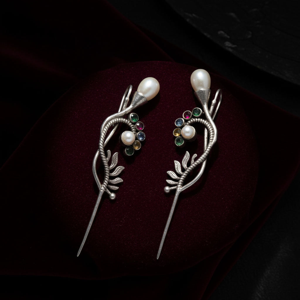 Pair of silver earrrings with pearls and gemstones on a dark background
