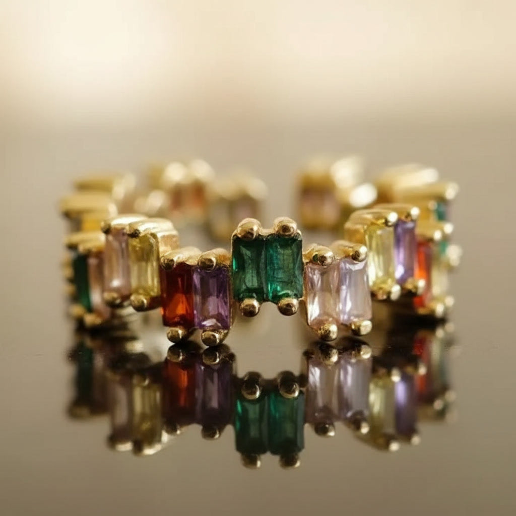 Gold ring with multicolored gemstones on a reflective surface