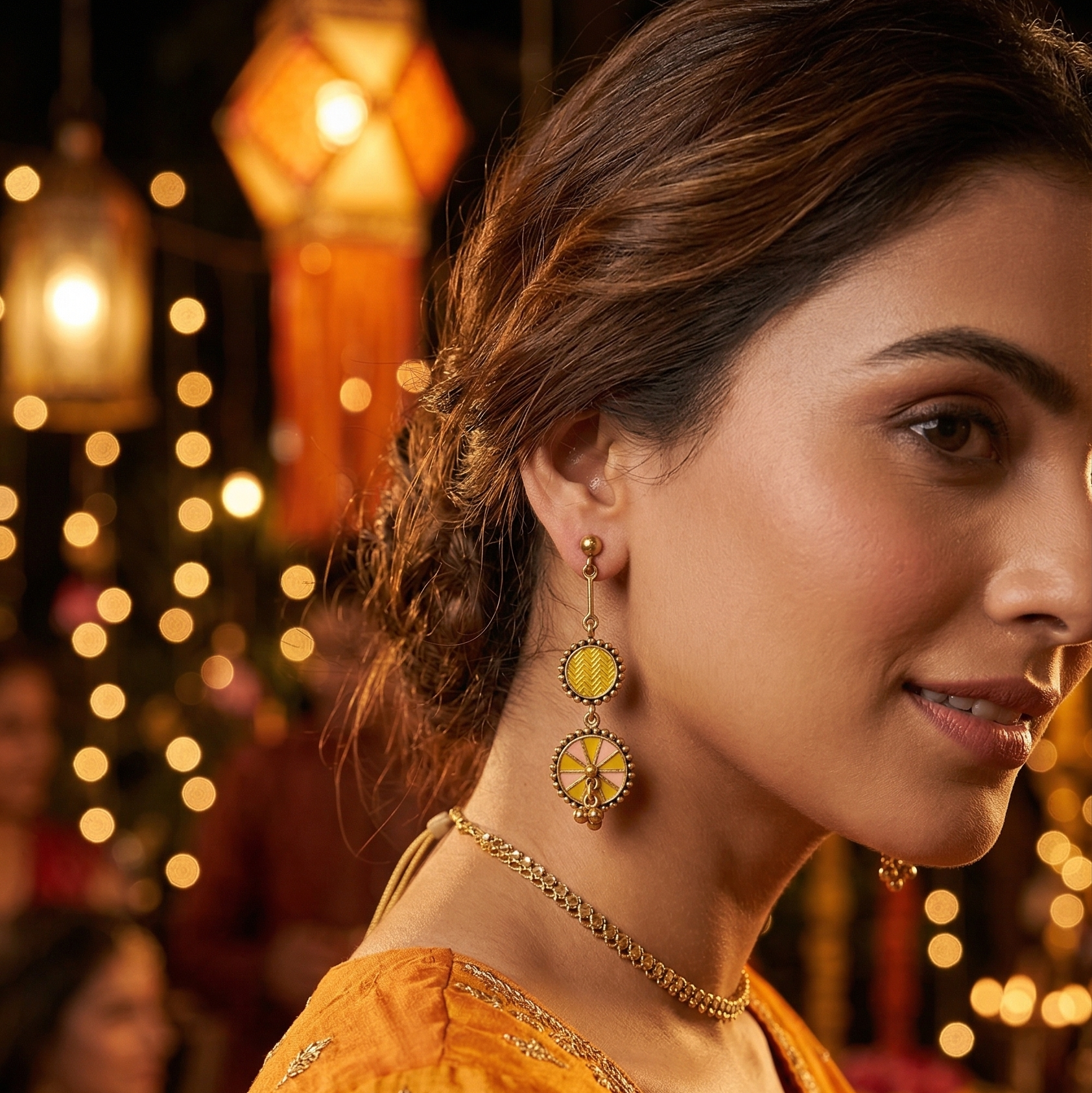 Woman wearing Yugavi Ishnavi mustard yellow and blush pink enamel double disc drop earrings — gold bead border discs with geometric upper disc and chakra wheel lower disc, styled with white fabric for everyday or festive wear