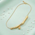 Gold necklace with a lion head charm on a light green background with scattered pearls.