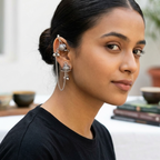 Yugavi Avisha oxidised silver teapot ear cuff chain earring worn on ear — upper cartilage cuff with miniature teapot charm and ghungroo balls, fine double chain draping along outer ear, lower lobe stud with second matching teapot charm and ball drops, full two-teapot composition visible, hair pulled back, House of Yugavi Kavya Collection