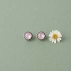 Yugavi Bindu minimalist silver stud earrings — round white moonstone or mother of pearl cabochon in twisted rope silver bezel setting, push-back stud closure, displayed as a pair on taupe fabric