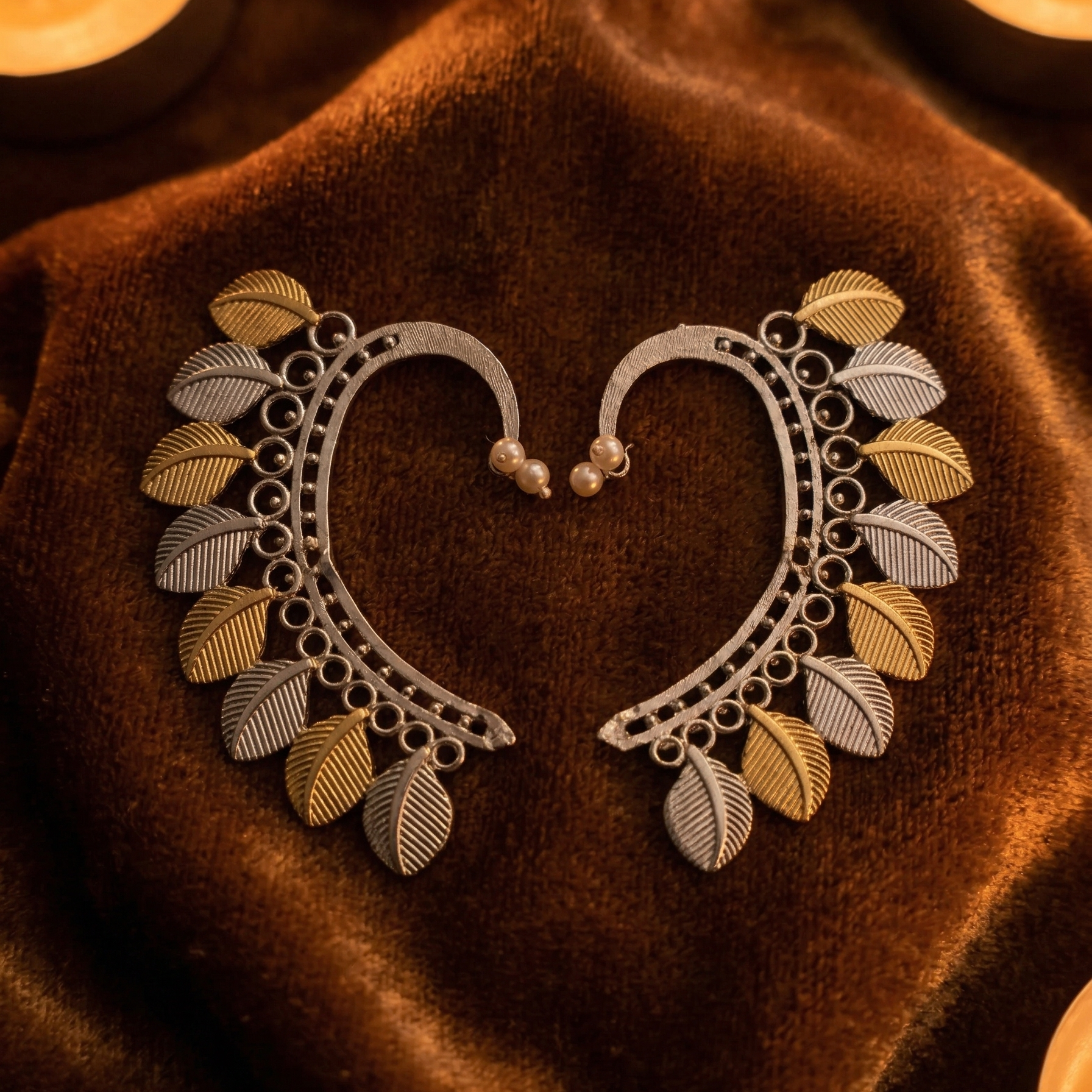 Yugavi Dvitīya dual-tone ear sweep pair angled view — rhodium silver arc with beaded border, alternating gold and silver engraved ribbed leaf cascade, pearl ball stud fitting — House of Yugavi