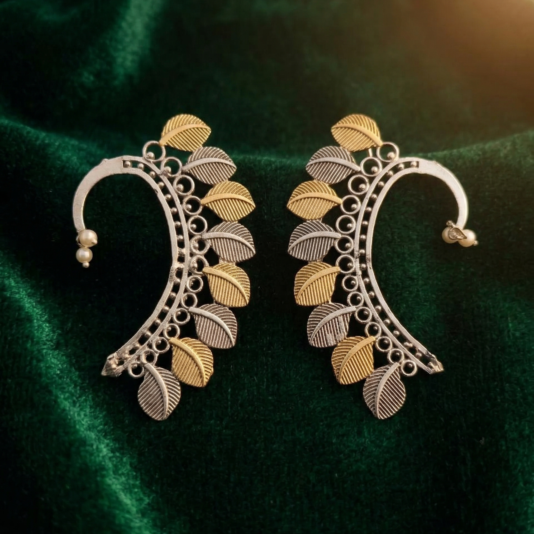 Yugavi Dvitīya dual-tone leaf cascade ear crawler pair front view — full arc frame with open circle links, alternating rhodium and gold ribbed leaves, mirrored left and right design — House of Yugavi
