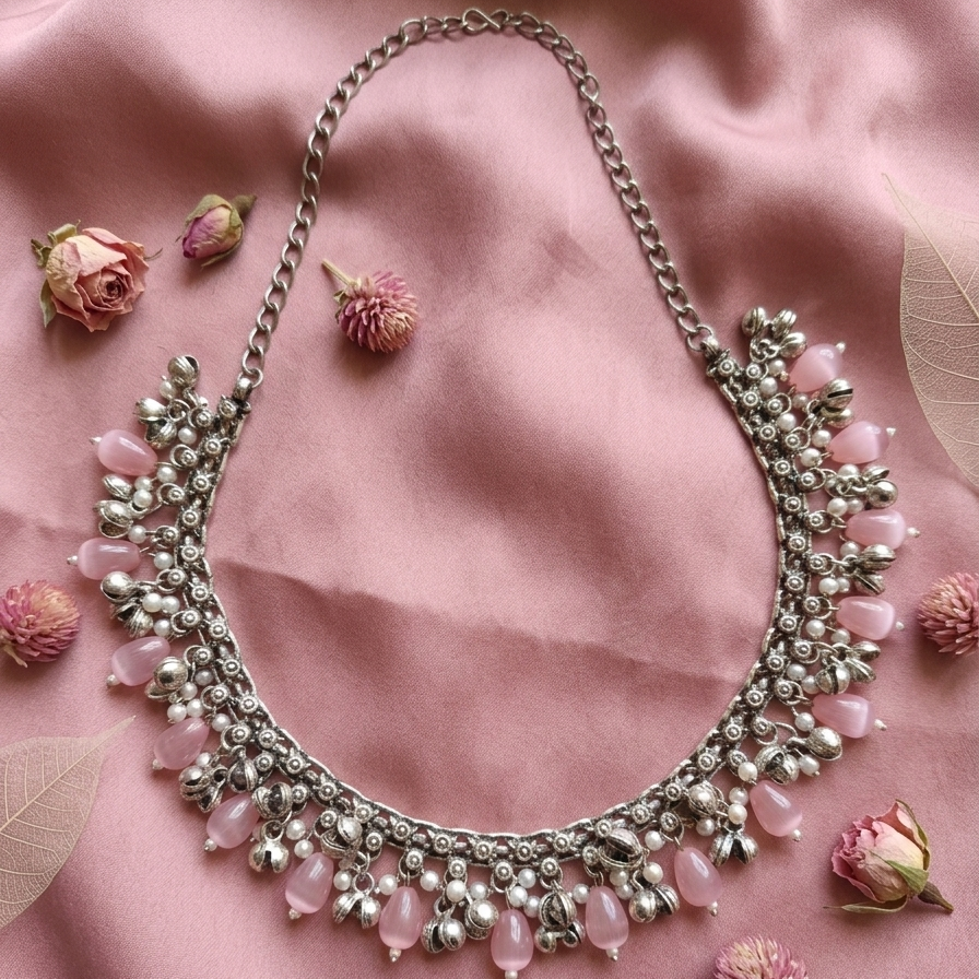 Yugavi Madhuri silver charm fringe collar necklace — curved silver chain with continuous fringe of blush pink oval cat's eye beads, seed pearls and silver floral charm connectors along inner edge, lobster clasp with chain extender