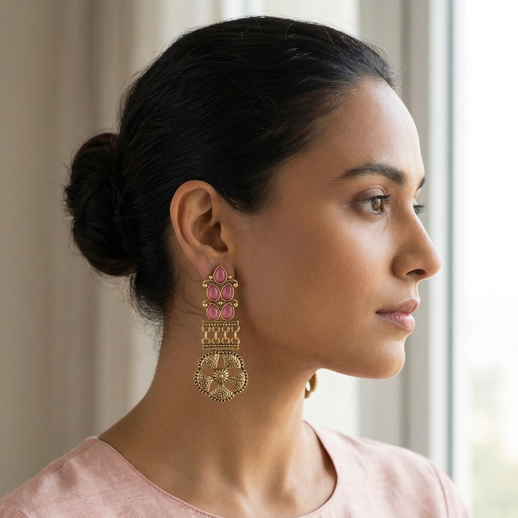 Yugavi Navira antique gold rose stone drop earrings displayed as a pair on white background — three rose pink cat's eye oval cabochons in fan cluster with gold filigree, narrow chain link bar connector, and large open four-petal flower disc with hammered texture and bead-dot border