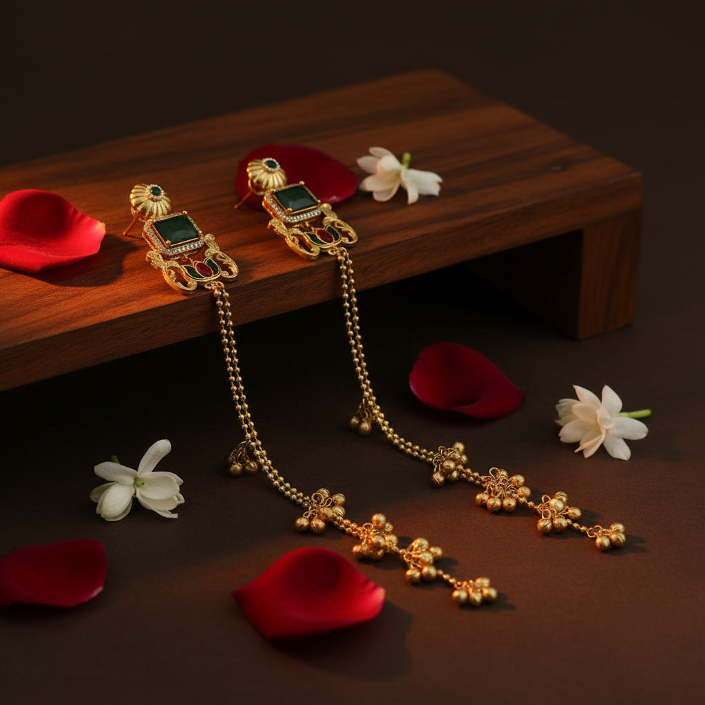 Gold necklace with green gemstones on a wooden stand with red and white flowers.