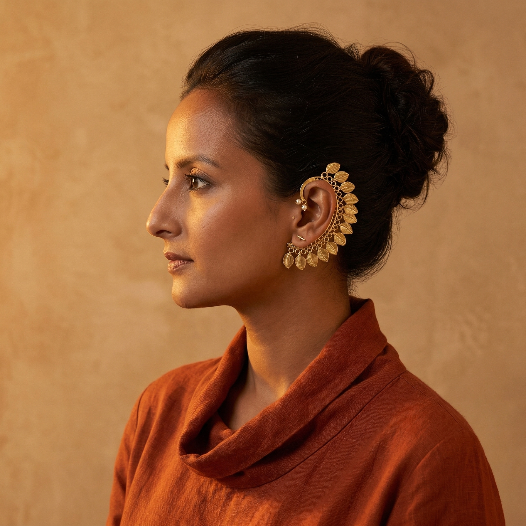 Yugavi Pallava brass heritage ear cuff pair — crescent arc with beaded border, fan of engraved ribbed leaf drops in graduated width, pearl ball fitting, warm gold finish 