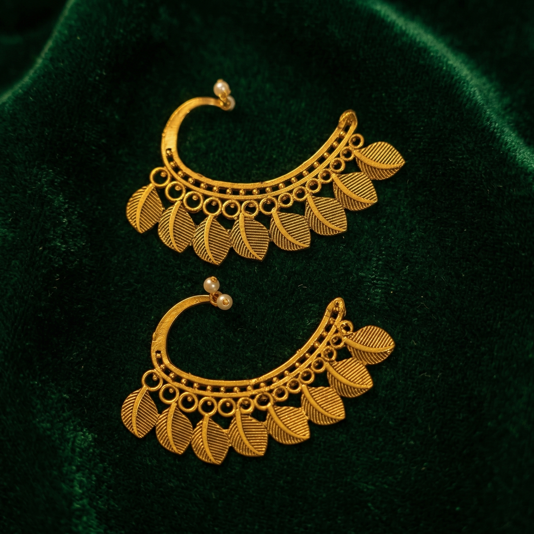 Yugavi Pallava ear cuff close-up — individually engraved ribbed leaf drops fanning from beaded arc border, warm brass gold finish, leaf vein detail visible 
