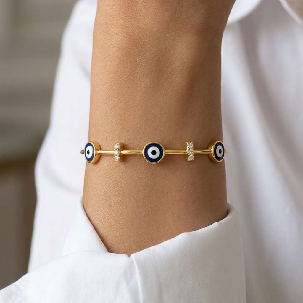 Gold bracelet with eye design on a wrist against a white shirt background