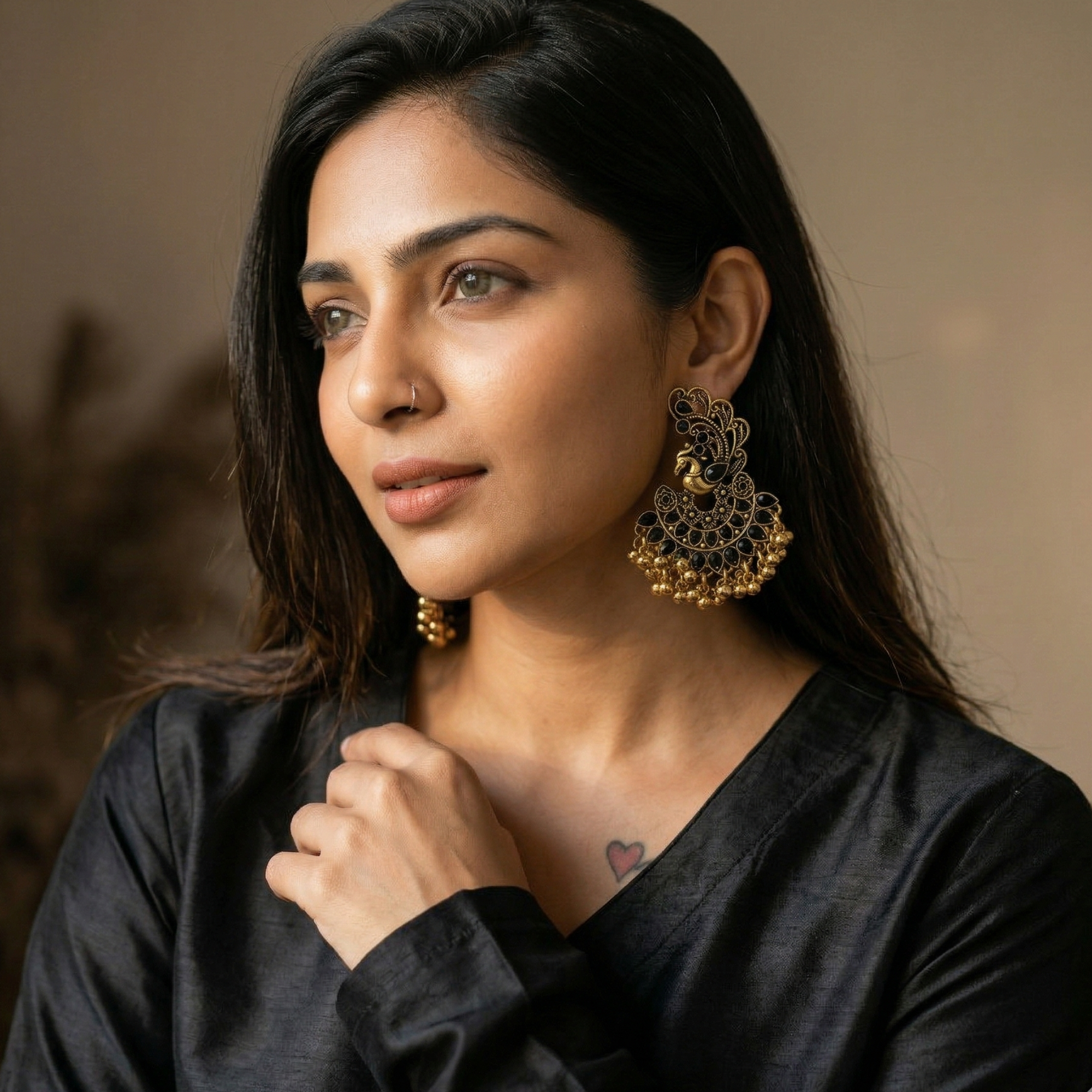 Yugavi Priyana antique gold peacock chandbali earrings displayed as a pair on white background — open-work Mayura motif with black oval and teardrop stone feathers at crown, wide crescent fan base with black teardrop petal stones, gold ghungroo ball fringe drops at base