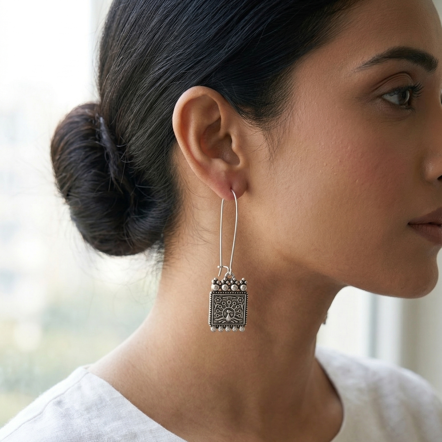 Yugavi Raksha oxidised silver rectangle tablet drop earrings displayed as a pair on white background — long elongated oval wire hooks, rectangular pendants with dot-bead border, five-ball crown with filigree lace, folk-engraved peacock under tree of life with flower corner motifs, five silver ball base fringe