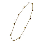 Yugavi Saisha gold multi-heart station necklace worn at collarbone — delicate gold cable chain with multiple small puffy 3D gold hearts evenly spaced along full length, shown on model in beige shirt collar, bright gold finish