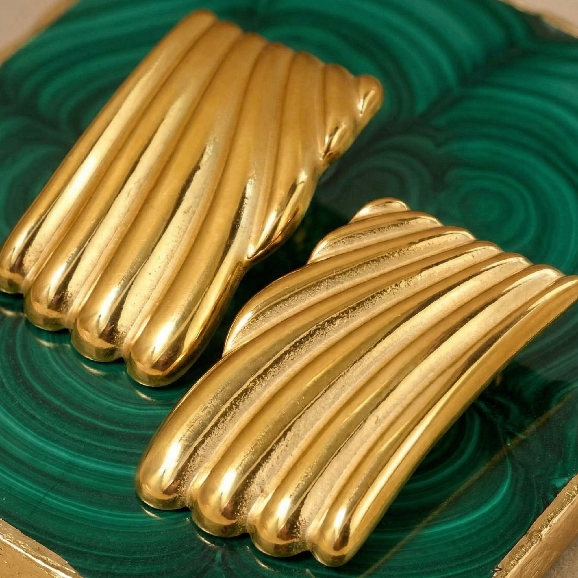 Gold earrings on a green and gold decorative background