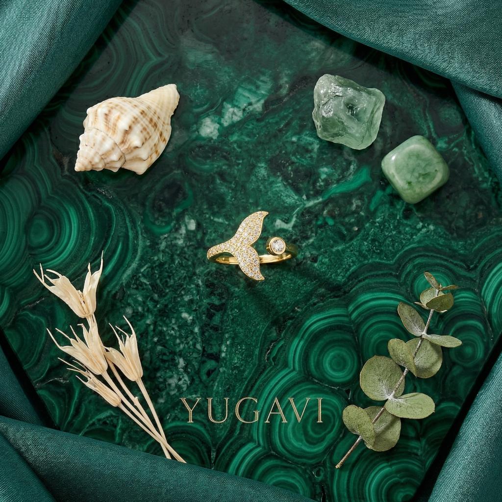 Gold ring on a green marbled surface with crystals and leaves, branded 'YUGAVI'.