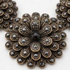 Decorative brooch with floral design and black gemstones on a white background